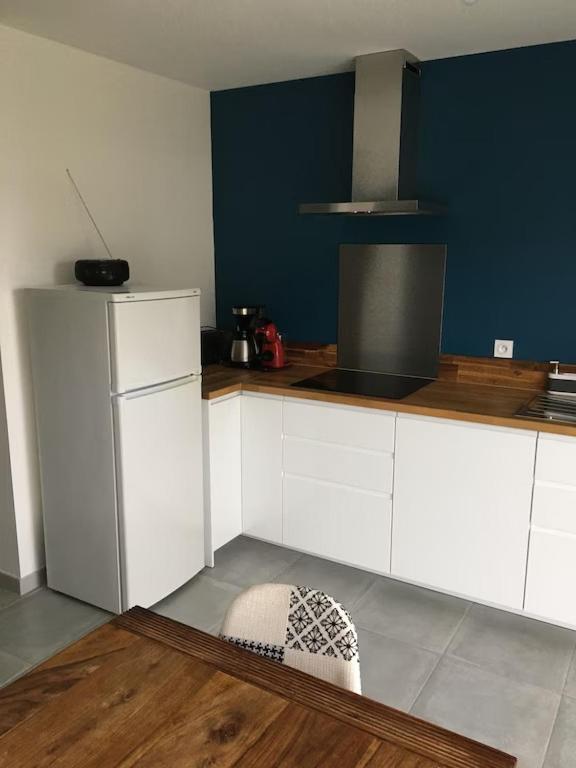 a kitchen with white cabinets and a blue wall at Maison située entre plage la mine d'or et bourg in Pénestin