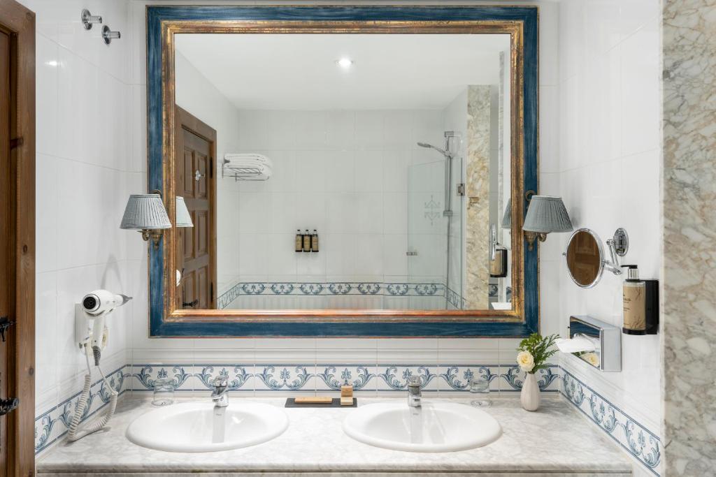 uma casa de banho com 2 lavatórios e um espelho grande em Parador de Lerma em Lerma