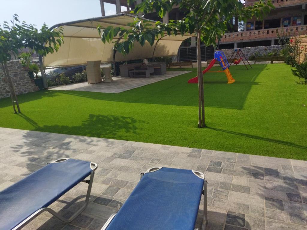 une aire de jeux avec deux bancs bleus dans un parc dans l'établissement Tzoli Residence, à Kalamaki