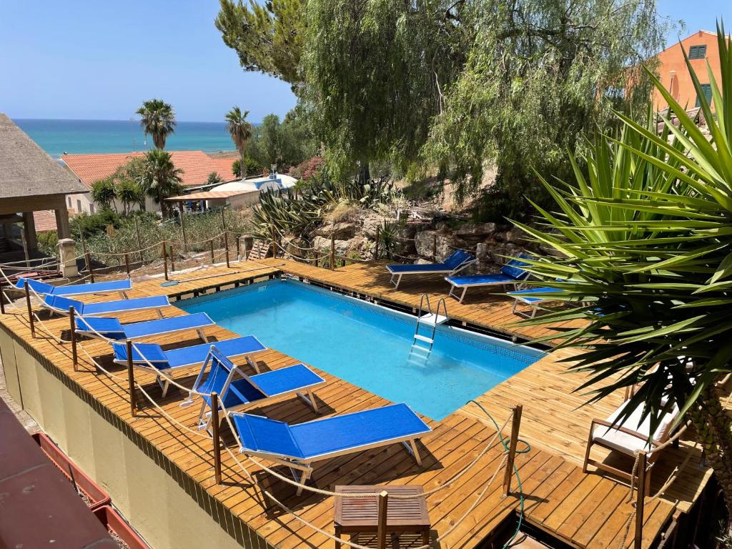 a swimming pool with blue lounge chairs and a swimming pool at Holiday Beach Lumia in Sciacca