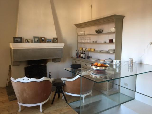 cocina con mesa de cristal y chimenea en Rooftop apartment in Medieval Italian City, en Foligno