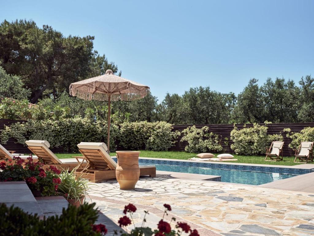 a patio with an umbrella and chairs and a pool at La Maison Du Maire Luxury Villa in Sarakinádhon