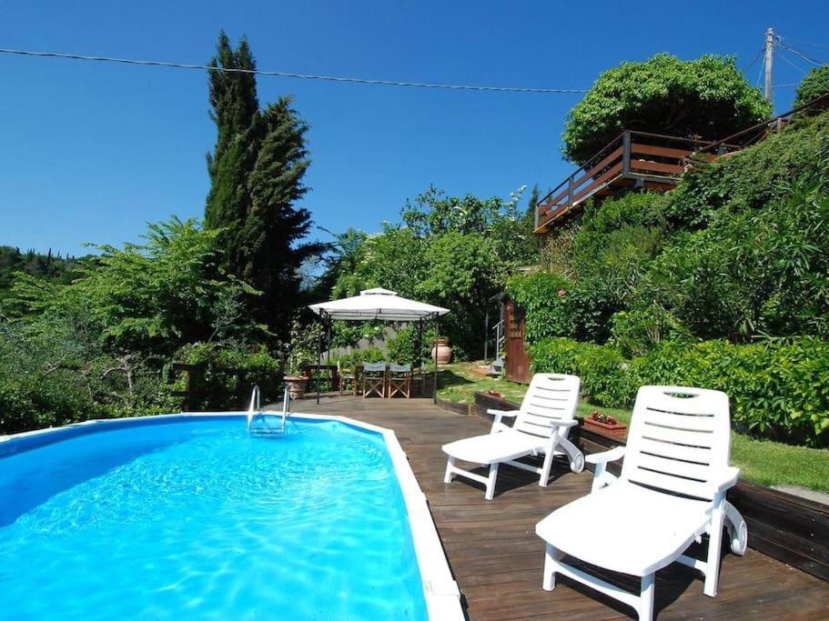 een zwembad met 2 stoelen en een tafel en een parasol bij Country House in Chianti Da Vieri in Certaldo