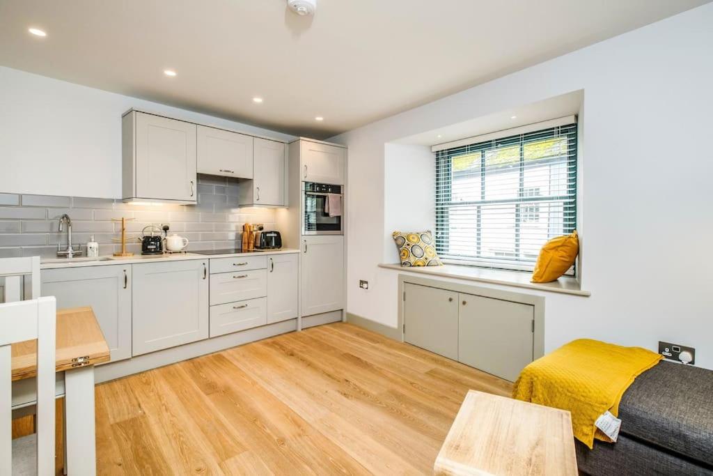 a kitchen with white cabinets and a wooden floor at Hawkers Padstow in Padstow