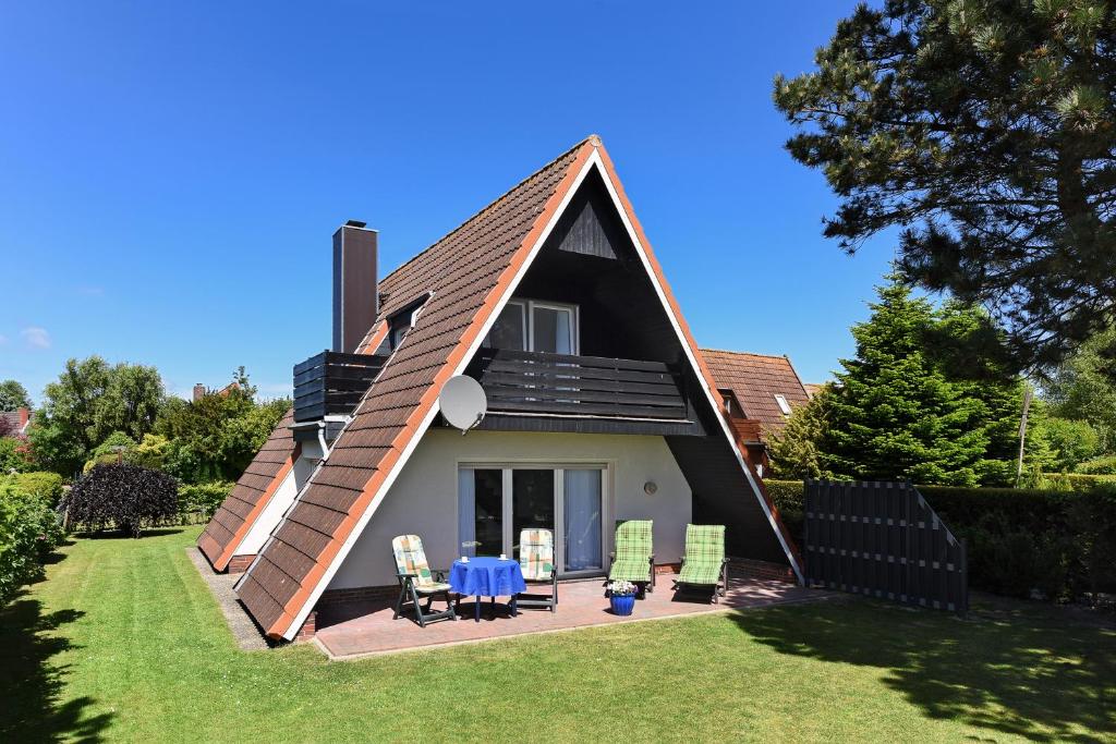 a house with a gambrel roof with a table and chairs at Ferienhaus Am Tief in Neuharlingersiel