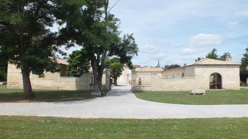 une maison en pierre avec un arbre et une passerelle dans l'établissement La Chapelle du Domaine de Choisy, à Abzac
