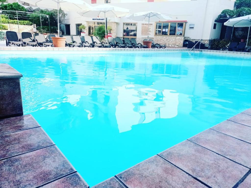 une piscine d'eau bleue dans un hôtel dans l'établissement The San Anton Hotel, à San Pawl il-Baħar