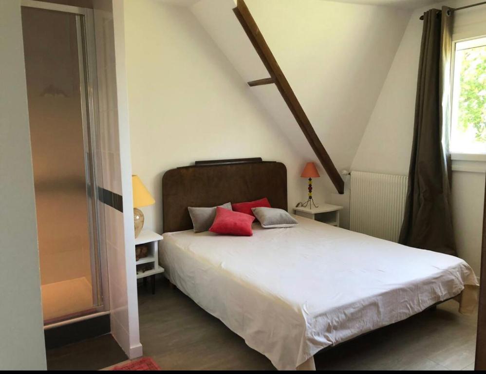 a bedroom with a white bed with two red pillows at SGDB in Sainte-Geneviève-des-Bois