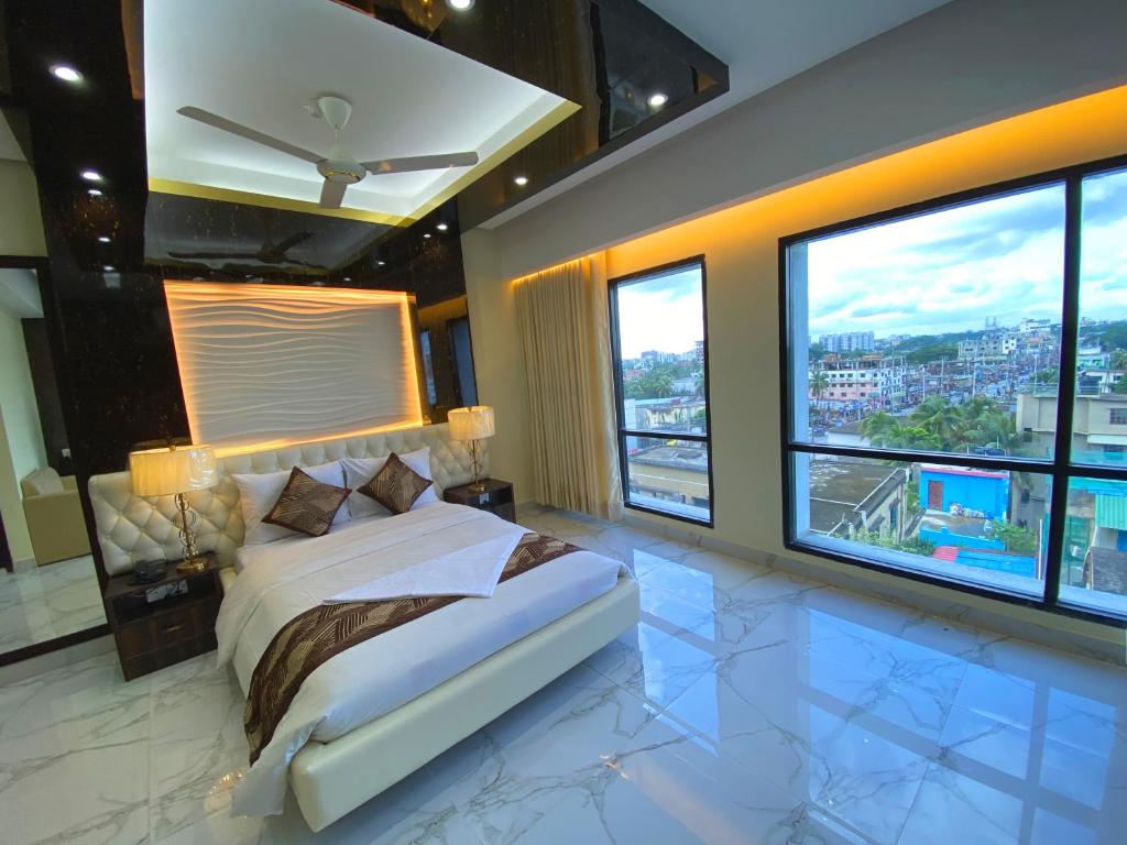 um quarto com uma cama grande e janelas grandes em Hotel Valentino em Noākhāli
