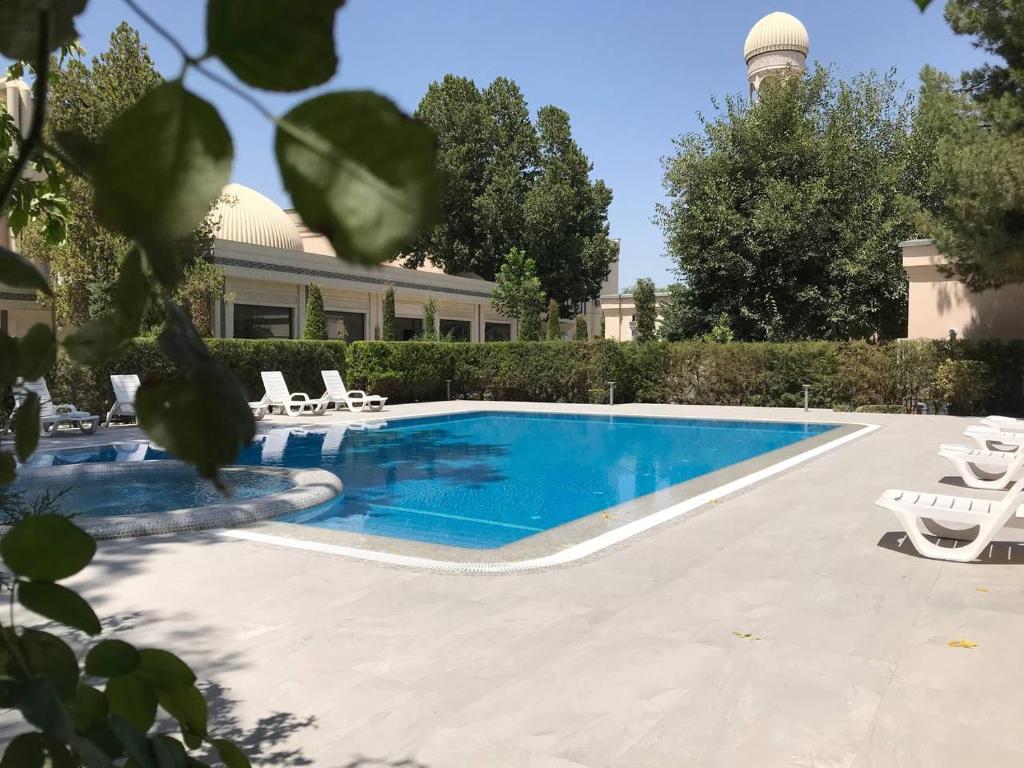 una piscina con sillas y un edificio en Orient Star Hotel, en Samarkand