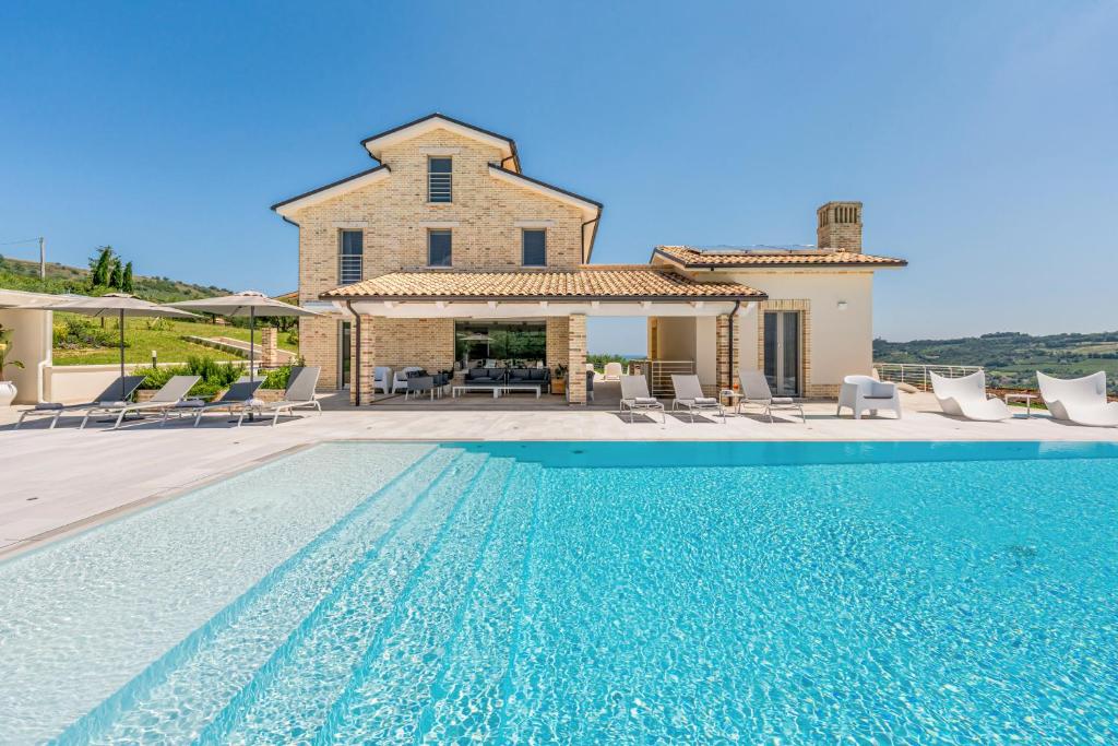 una villa con piscina di fronte a una casa di Villa Ada a Lapedona