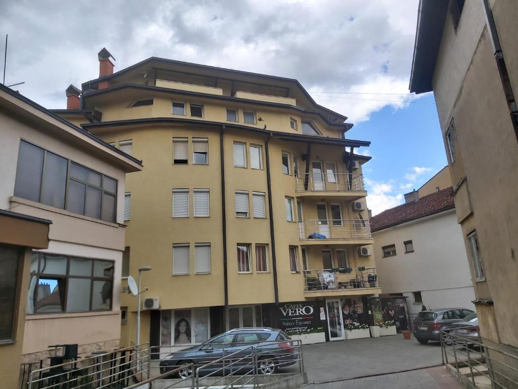 un edificio amarillo con un coche aparcado delante de él en Vranje City Center, Penthouse Delux Apartment en Vranje