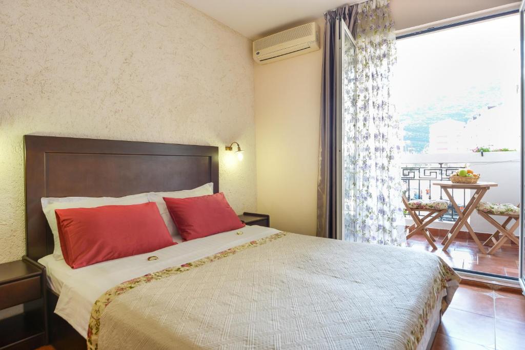 a bedroom with a large bed with red pillows and a window at Hotel Villa Perla Di Mare in Budva