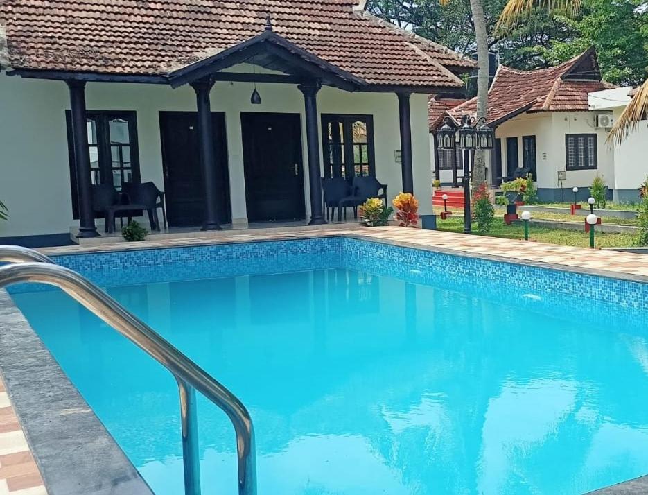 a swimming pool in front of a house at Winterfeel Resort in Alleppey