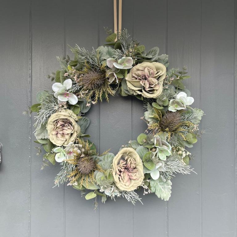 a wreath with flowers on a gray door at The Bubble Hideaway - A Little Oasis near the Sea in Whitstable