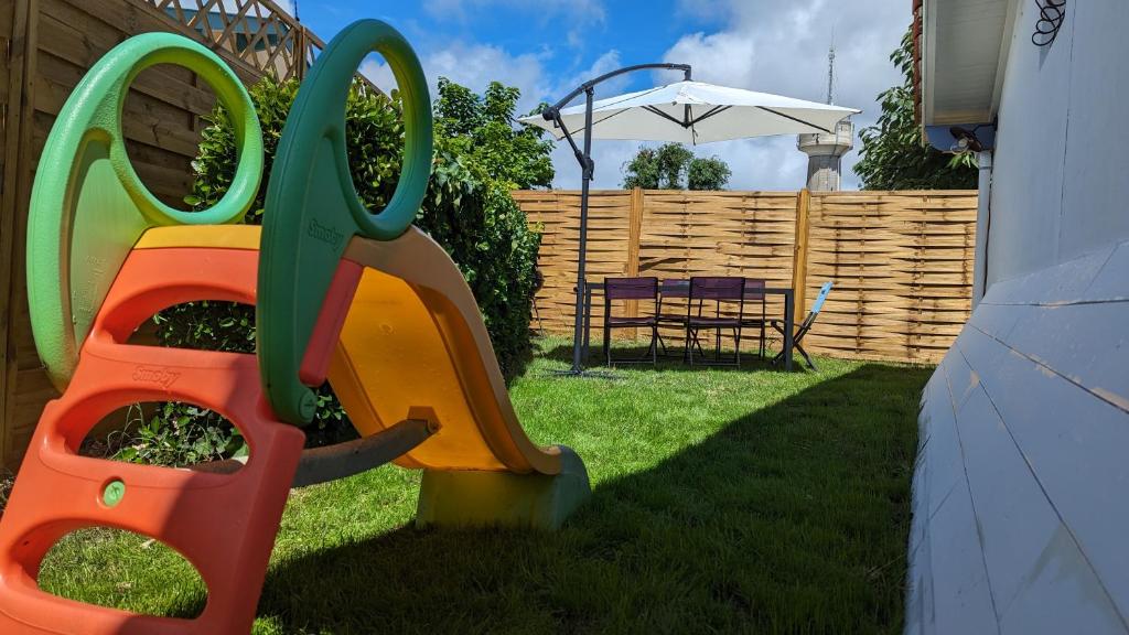 a childs play equipment in a yard with a fence at Andernos-Maison de centre-ville avec jardin in Andernos-les-Bains