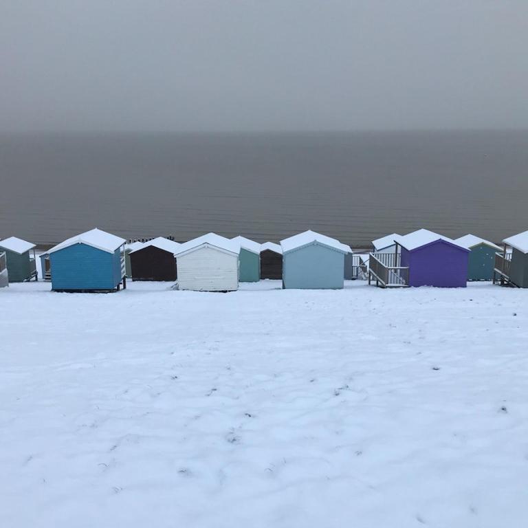 a row of beach huts in the snow at The Bubble Hideaway - A Little Oasis near the Sea in Whitstable