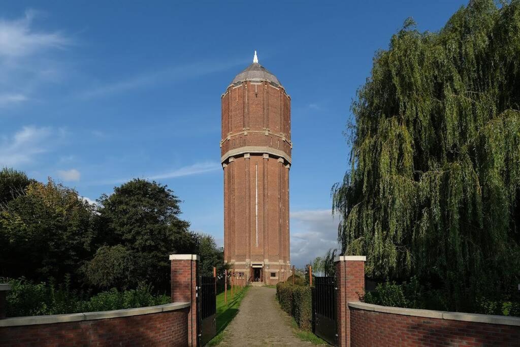 una gran torre de reloj de ladrillo en un jardín con una valla en Groeps- en retreat/trainings-locatie De Waterkroon!, en Wieringerwaard