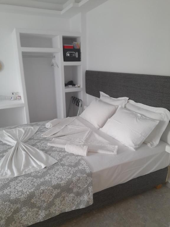 Cama blanca con sábanas y almohadas blancas en Sand rooms Antiparos en Andiparos