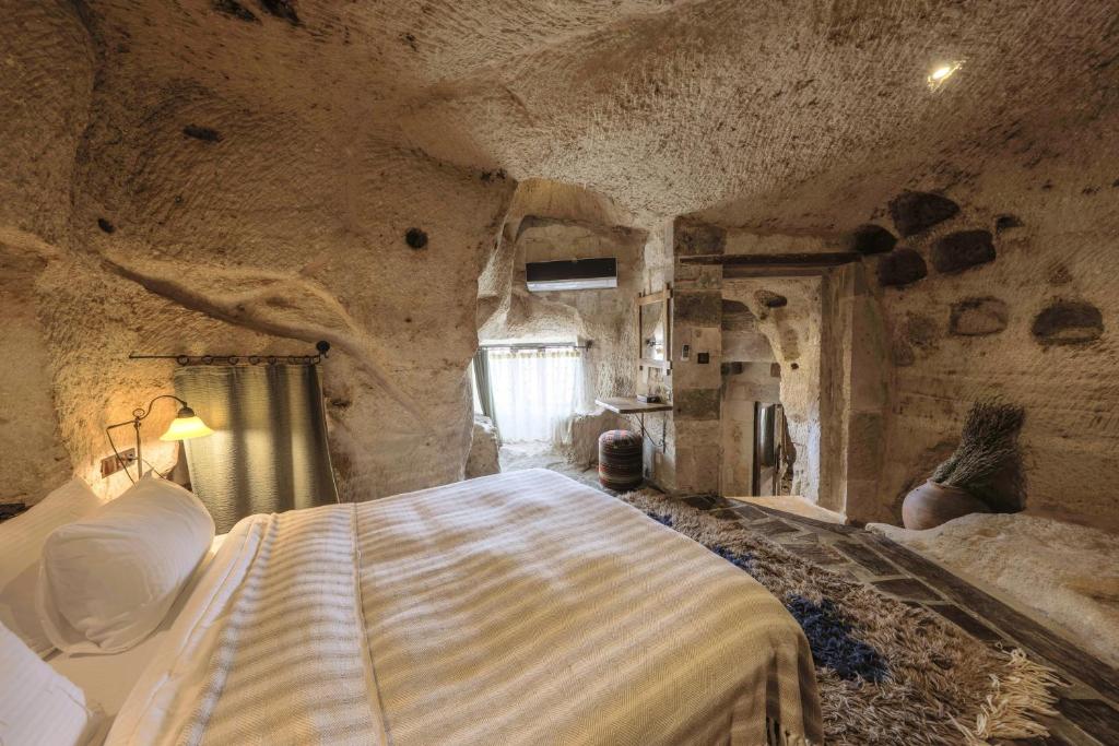a bedroom with a large bed in a stone room at Kelebek Special Cave Hotel & Spa in Göreme