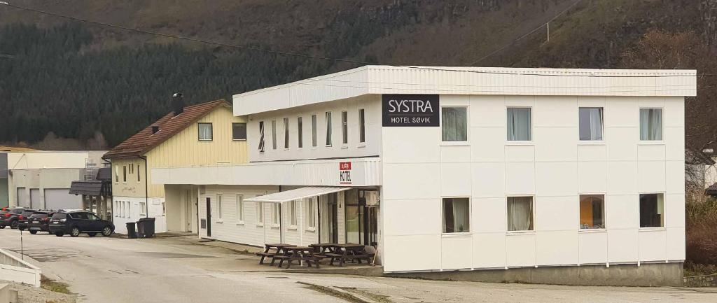 a white building with a sign on the side of it at Systra Hotel Søvik in Syvik