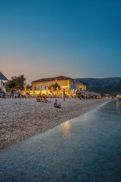 a person sitting on a beach near the water at Hotel Dobrovit in Baška