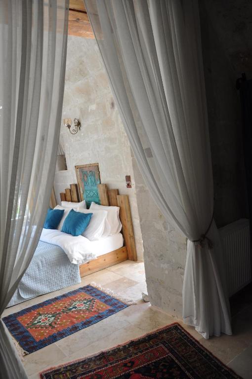 a bedroom with a bed with blue and white pillows at cemil köyü cave house in Ürgüp