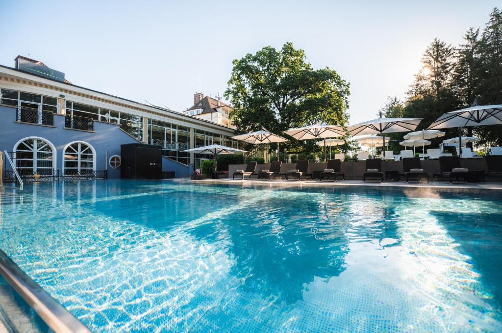 a large swimming pool with chairs and umbrellas at Steigenberger Hotel Der Sonnenhof in Bad Wörishofen