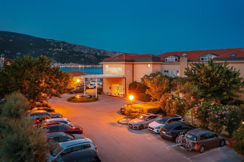 a parking lot with cars parked in front of a building at Hotel Dobrovit in Baška