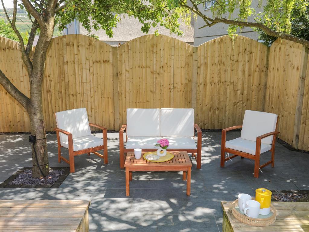 two chairs and a table in a yard with a fence at Maes Y Ffynnon in Pwllheli