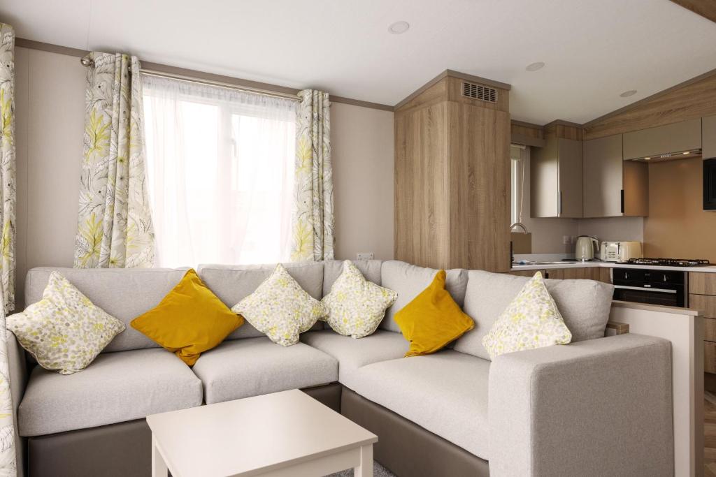 a living room with a gray couch with yellow pillows at TILLINGHAM CARAVAN 3 bed 2 bath caravan. in Great Clacton