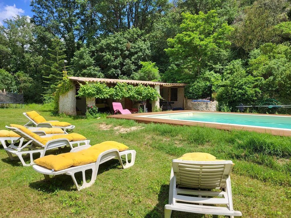 un groupe de chaises longues et une piscine dans l'établissement Le moulin des rocs, à Rians