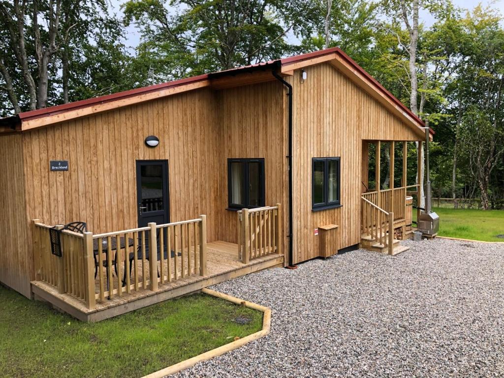 a log cabin with a porch and a deck at Breckland Lodge 2 with Hot Tub in Belladrum