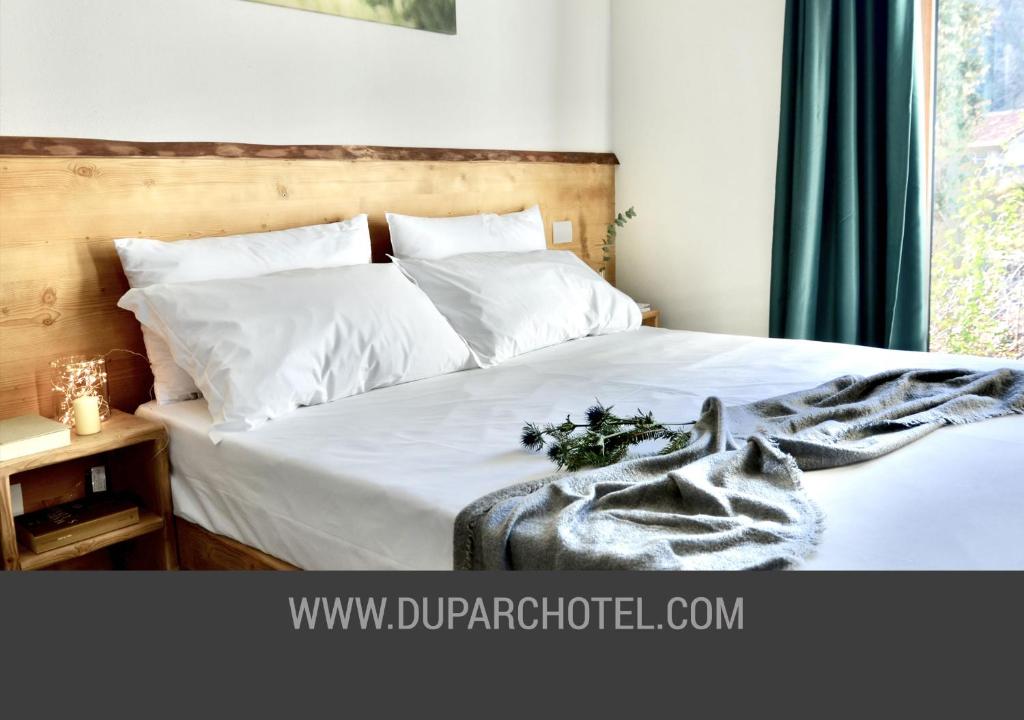 una camera da letto con un letto bianco con una coperta sopra di Apartments Du Parc a Sauze d'Oulx
