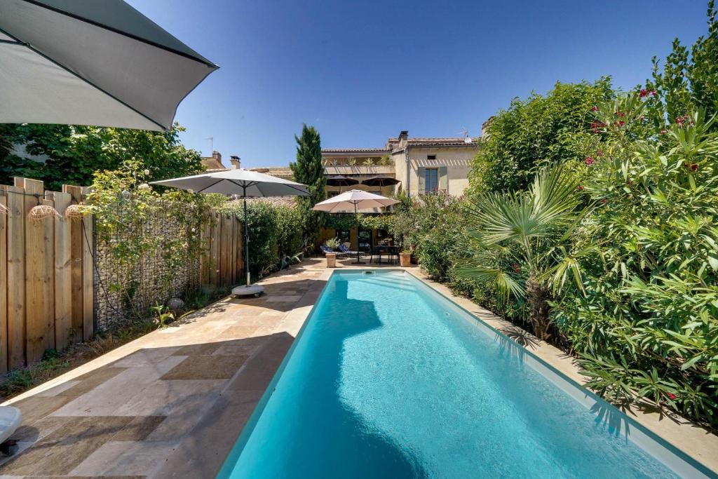 a swimming pool in a backyard with an umbrella at Le Castel de Castillon - Maison d'exception à 10 minutes de Saint Emilion in Castillon-la-Bataille