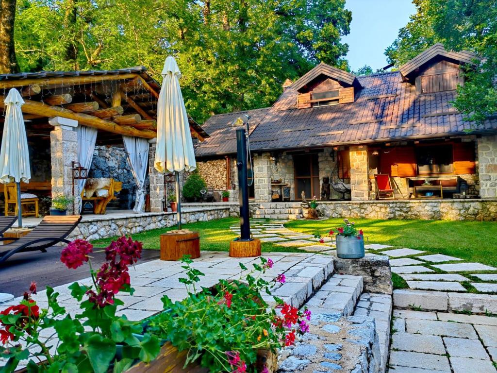 a house with an umbrella and flowers in front of it at Luxury Chalet Regina in Bruvno