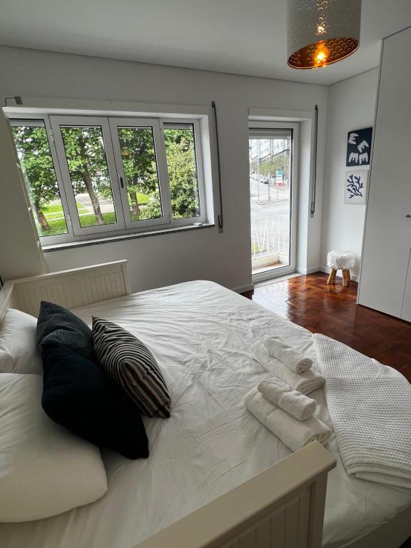 1 cama blanca grande en una habitación con ventanas en Casa da Praça, en São João da Madeira