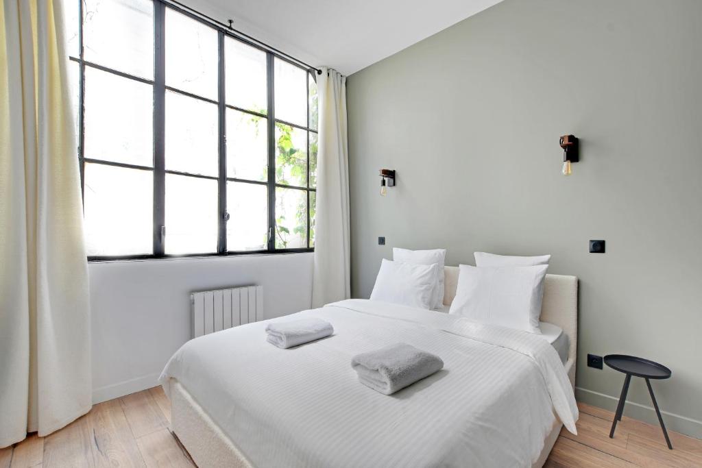 a white bedroom with a large bed with two towels on it at GemBnB Luxury Apartments - Sedaine in Paris