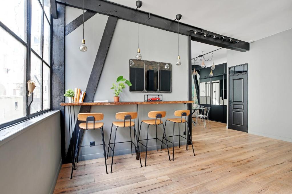 an industrial kitchen with a bar and stools at GemBnB Luxury Apartments - Sedaine in Paris