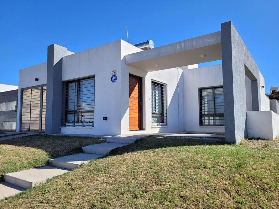 ein weißes Haus mit einem Rasenplatz davor in der Unterkunft Casa Amplia y Tranquila con Garage in Alta Gracia