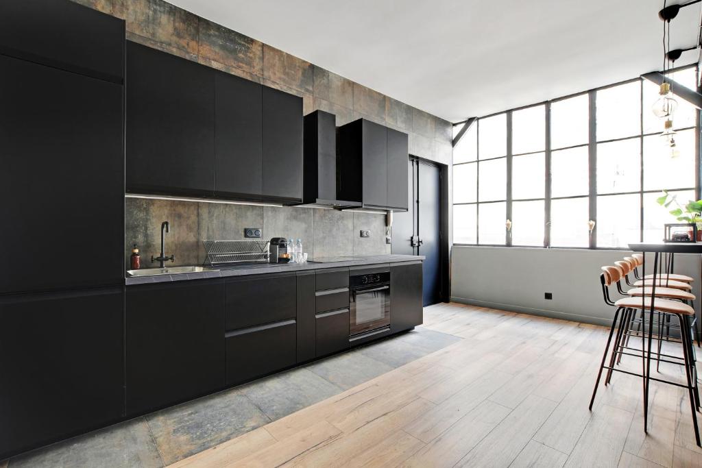 a kitchen with black cabinets and a table and chairs at GemBnB Luxury Apartments - Sedaine in Paris