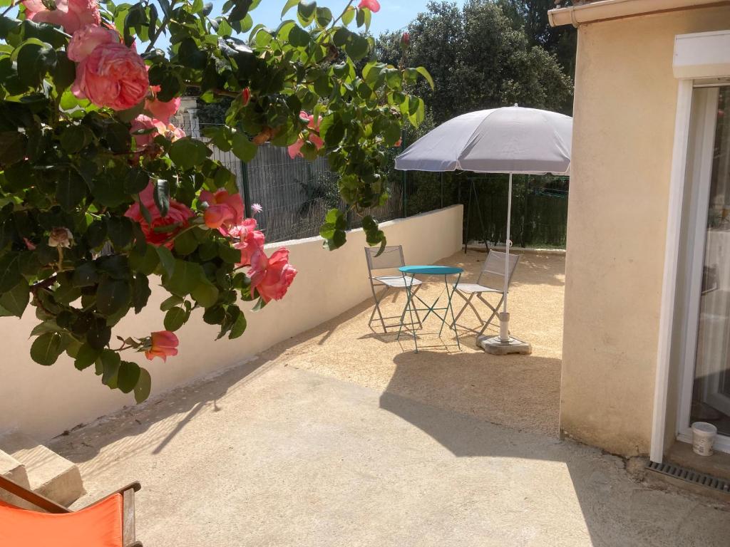 un patio con mesa, sillas y sombrilla en Petite maison avec terrasse et piscine en Beaucaire