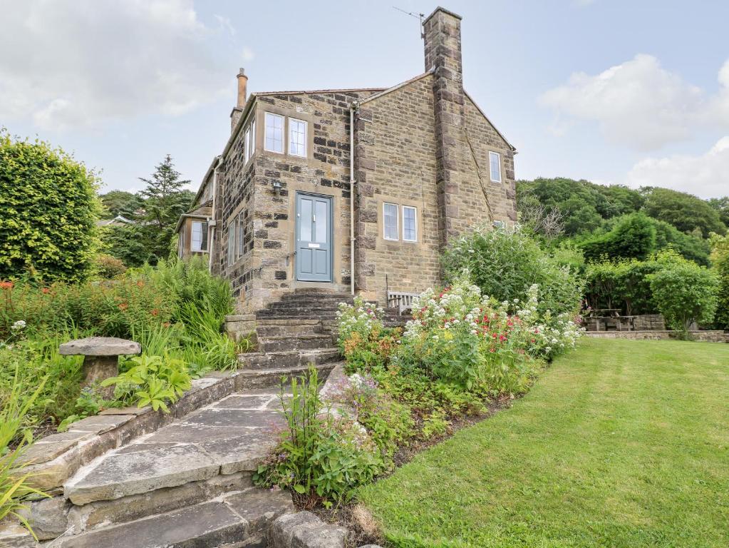 an old stone house with a garden in front of it at Fern Cottage in Bakewell