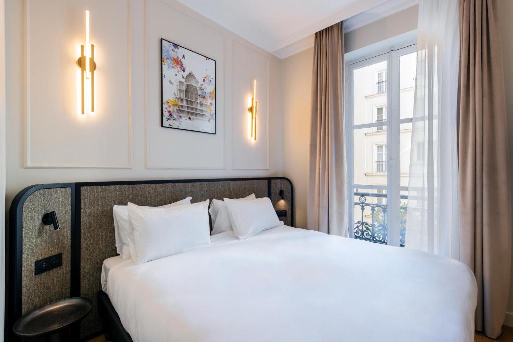 une chambre avec un grand lit blanc avec une fenêtre dans l'établissement Aparthotel Adagio Paris Opéra, à Paris