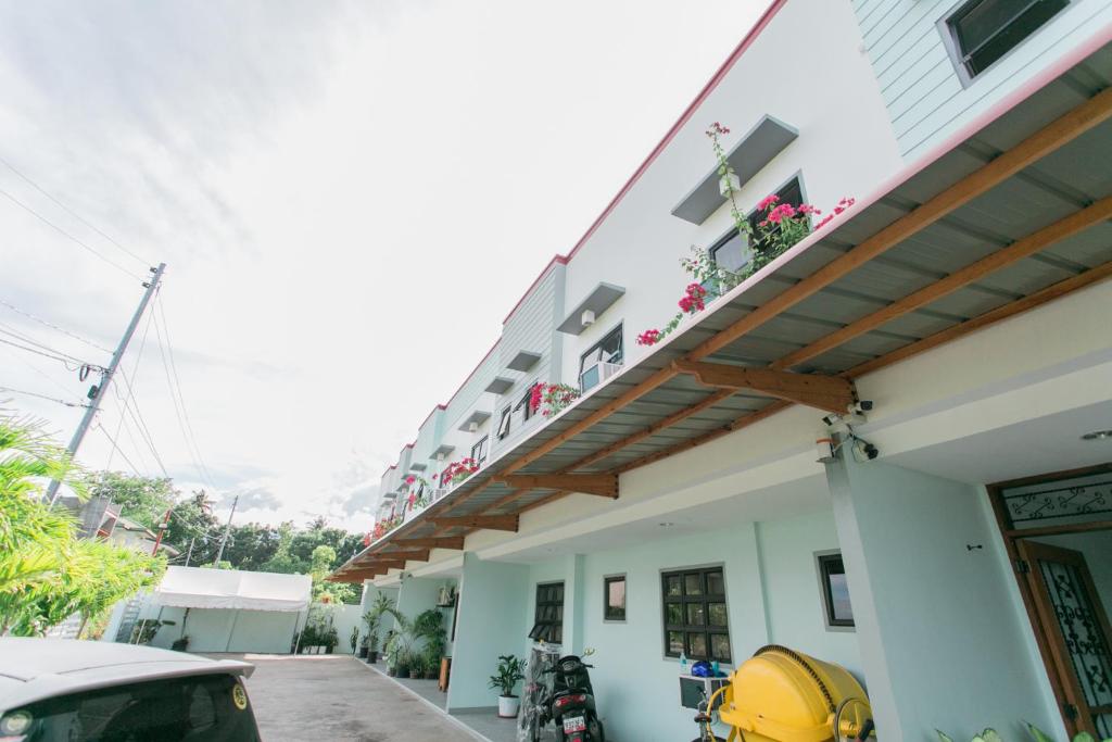 Midway Stay Apartments Dumaguete في دوماغيتي: مبنى مع شرفة عليها زهور