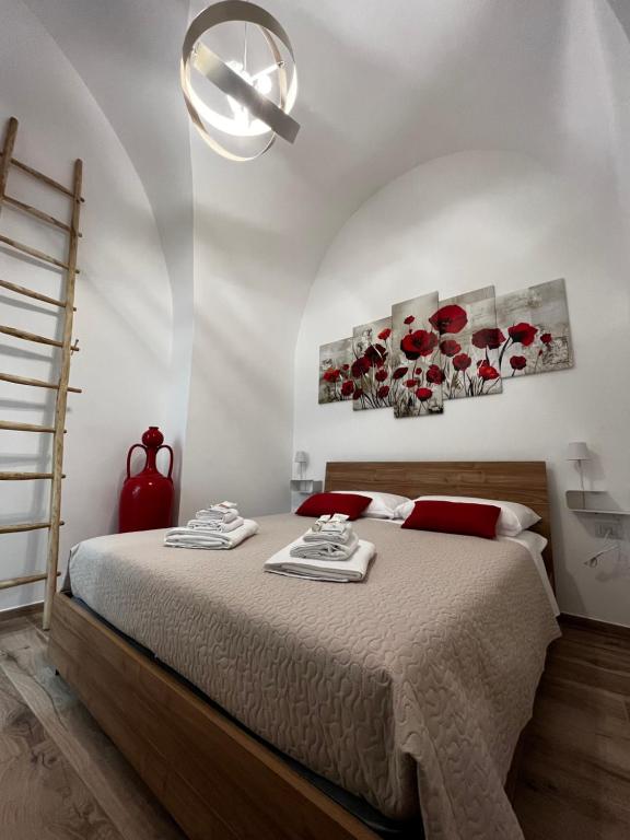 a bedroom with a bed with red roses paintings on the wall at Dimora Nonno Ciccio in Polignano a Mare