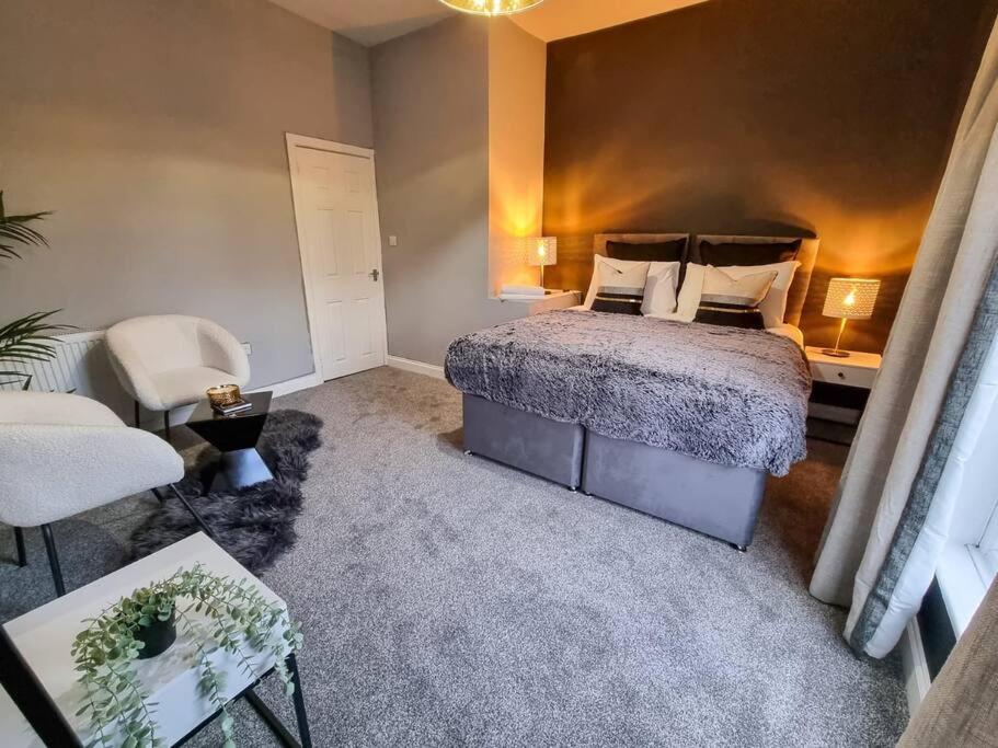 um quarto com uma cama, um sofá e uma cadeira em 3 BR Home Close to MCR City Centre em Manchester