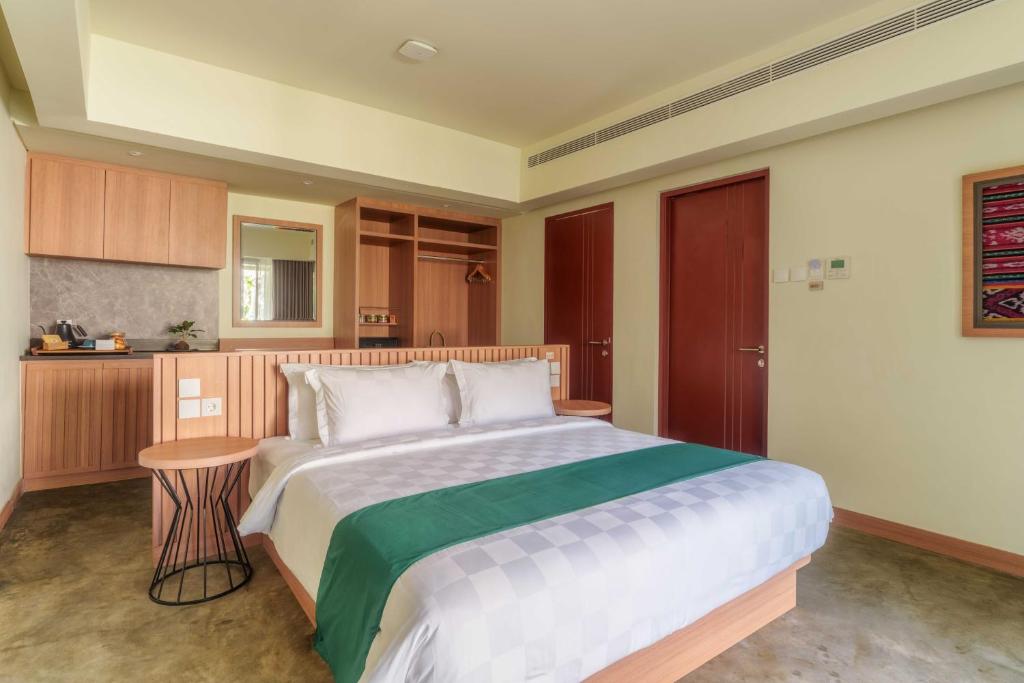 a bedroom with a large bed and a kitchen at Ayom Suite in Mataram