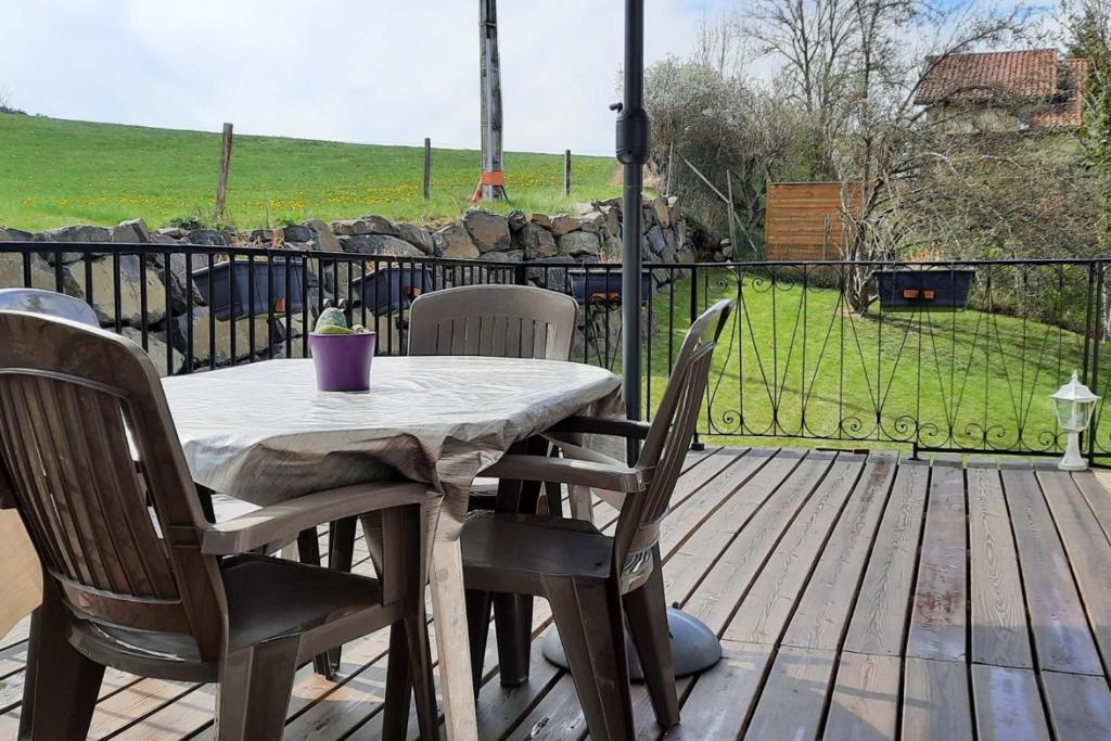 einen Tisch und Stühle auf einer Terrasse mit einem Zaun in der Unterkunft Villa Magnolia 8 personnes in Coubon