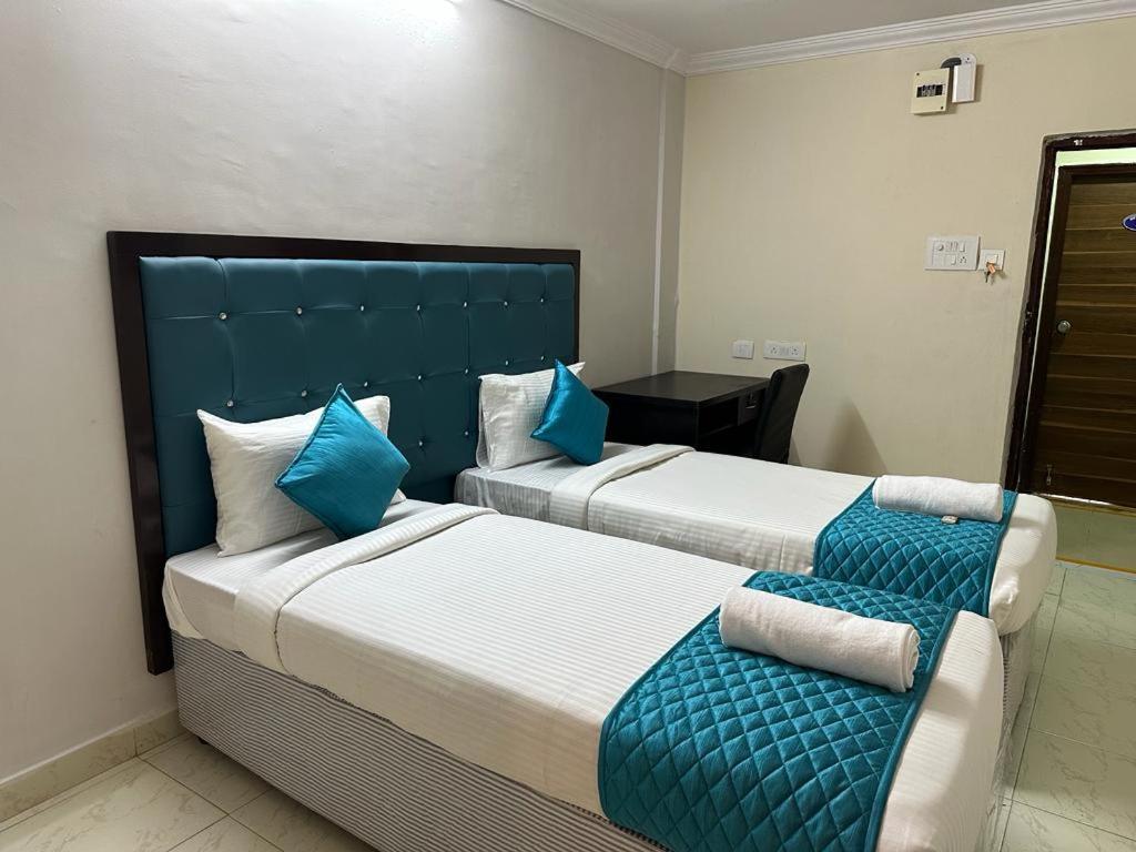 two beds with blue pillows in a hotel room at Hotel Skymoon Luxury Rooms in Hyderabad